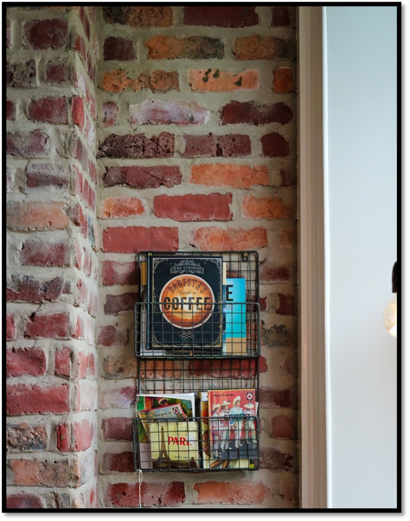 A brick wall with a book rack and moldy bricks