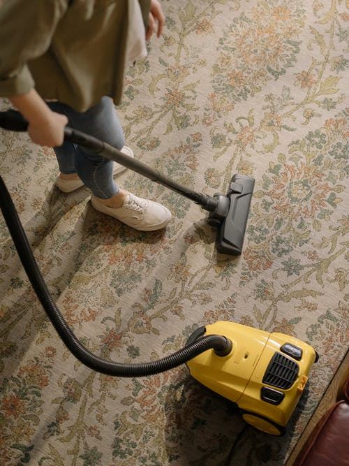  a person doing vacuum over a carpet