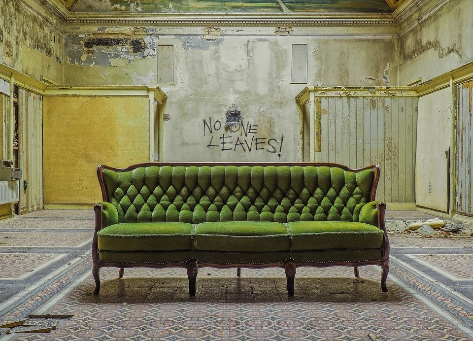 a room with a green couch and walls infested with mold