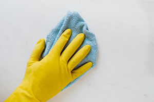 A professional cleaner wiping the kitchen wall wearing a rubber glove
